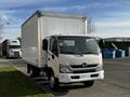 A 2015 Hino 195 box truck with an open driver's door parked on the street