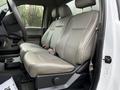 The interior of a 2017 Ford F-350 SD showing leather seats in a light color with a console and armrest between the front seats