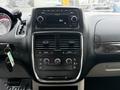 Dashboard of a 2011 Dodge Grand Caravan featuring audio controls and climate settings with a display screen above