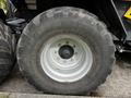 A large tire mounted on a metal rim labeled Redesten with visible treads and bolts showcasing a rugged design for agricultural use
