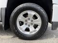 A close-up of a silver wheel rim of a 2018 Chevrolet Silverado 1500 with a black tire displaying the Firestone logo and all-terrain tread design