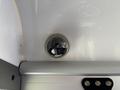 A round overhead light fixture installed in a vehicle's interior with a reflective surface and visible electrical wiring around the base