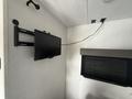 A mounted flat-screen television attached to a wall with cables connected nearby