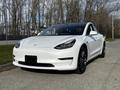 A white 2019 Tesla Model 3 parked on a concrete surface featuring sleek lines and a modern design