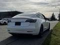 A 2019 Tesla Model 3 parked on the street showing its sleek design and distinctive rear with the Tesla logo on the trunk