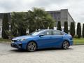 A blue 2021 Kia Forte with a sleek design is parked, showcasing its sporty profile and alloy wheels