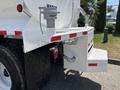 A 2015 Ford F-750 water truck with a large tank and visible hoses on the rear bed showcasing utility features and rugged tires