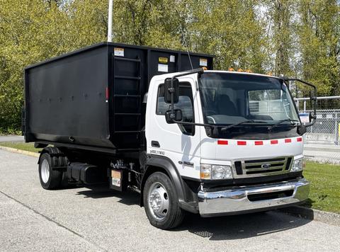 A 2009 Ford LCF 550 with a white cab and a black box truck bed parked on a street