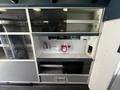 Interior storage area of a 2013 Chevrolet Express with cabinets shelves and various equipment including a hand sanitizer dispenser