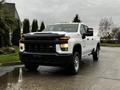 A white 2021 Chevrolet Silverado 3500HD with a black grille and chrome accents parked with its headlights on