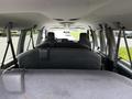 Interior view of a 2014 Ford Econoline showing rows of grey upholstered seats facing forward with seat belts attached to the sides