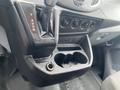 Interior view of a 2018 Ford Transit gear shift and center console with cup holders and various control knobs