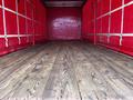 A 2008 Ford F-750 truck with an empty wooden cargo area featuring a red interior and vertical white straps along the sides