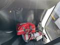 A red emergency bag and a fire extinguisher situated on the floor of a vehicle's cabin