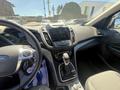 The interior of a 2014 Ford Escape featuring a steering wheel a console with a touchscreen and gear shifter along with seats and dashboard elements