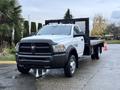 A 2018 RAM 5500 flatbed truck in white with a black grille and wheels parked on a wet surface