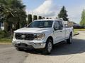 A white 2021 Ford F-150 pickup truck with a bold front grille and chrome accents parked on a paved surface