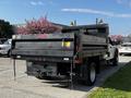 A 2021 Ford F-550 with a flatbed and side rails features amber lights mounted on the cab and a rear tow hitch