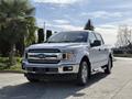 A white 2018 Ford F-150 pickup truck is prominently displayed in the foreground with a chrome grille and large tires