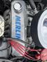 Close-up of a 1970 Chevrolet Corvette engine featuring a shiny silver valve cover labeled MERLIN with red ignition wires and an air filter on the side