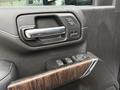Interior door handle and control panel of a 2022 GMC Sierra 3500HD featuring chrome accents and wood grain detailing