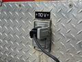 A close-up of a 2007 Ford F-550 with a 110 V electrical outlet mounted on a diamond plate surface