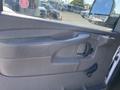 Close-up of the door panel of a 2012 GMC Savana featuring a handle and window control with a textured surface and armrest