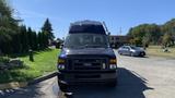 A 2013 Ford Econoline van parked in a lot with a front view showing its large windshield and grille