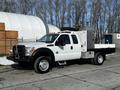 A 2011 Ford F-450 Super Duty flatbed truck with a white exterior and a tool box in the truck bed
