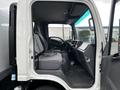 A 2022 Isuzu NPR with an open door showcasing its gray interior featuring seating for two and a dashboard with steering wheel and controls
