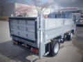 A 2008 Isuzu Elf truck with a flatbed design and a grey metallic finish parked in a lot