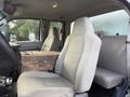 Interior of a 2008 Ford F-450 featuring two front seats with light gray upholstery and a wooden center console between them