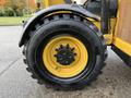 A close-up of a black tire with a yellow rim and visible lug nuts from a 2014 Caterpillar TL1055C heavy equipment machine
