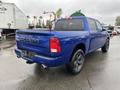 A blue 2019 RAM 1500 Classic truck with a crew cab and a standard bed viewed from the rear showing its iconic RAM logo and dual exhaust pipes
