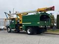 A green and yellow 2015 Freightliner M2 106 bucket truck with an elevated boom arm for maintenance work