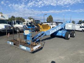 A blue 1997 Genie S-65 4X4 aerial work platform with a wheeled chassis and extended boom, designed for elevated work access and equipped with a safety cage