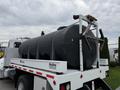 A 2016 Peterbilt 348 truck featuring a black tank mounted on a flatbed with reflective safety lights and a white Rollins branding on the side