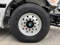 Close-up of a large truck wheel from a 2016 Peterbilt 348 featuring a shiny silver rim with multiple bolts and a thick black tire