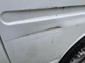 A 2014 GMC Savana with noticeable scratches and dents on the side panel showing signs of wear and tear