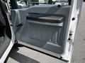 Interior door panel of a 2016 Ford F-550 featuring a grey design with a black armrest and manual door handle