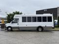 A white 2020 Chevrolet Express bus with large windows and a gray lower section is parked on a concrete surface