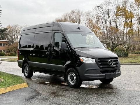 A black 2022 Mercedes-Benz Sprinter van parked with a sleek design and large windows standing out in the foreground