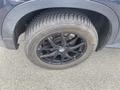 A black alloy wheel with a BMW logo and an all-season tire mounted on it, showing detailed tread pattern
