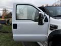 A 2009 Ford F-550 with an open door and a visible side mirror showcasing its white exterior and prominent features