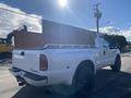 A 2000 Ford F-350 SD pickup truck with a wooden bed and black wheels viewed from the rear left side