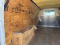 The interior of a 2012 Chevrolet Express van featuring a wooden storage box on the floor and bare walls with a metallic section in the back