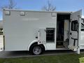 A 2013 Chevrolet Express emergency vehicle with a side door open revealing a compartment for equipment and interior seating visible