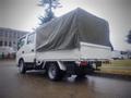 A white 2003 Toyota Toyoace truck with a covered bed and a flatbed design parked in a lot