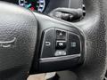 A close-up of the steering wheel controls of a 2020 Ford Transit with buttons for navigation and settings