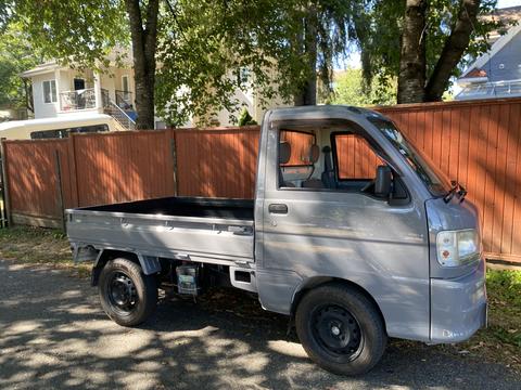 A 2000 Daihatsu Hijet truck with a compact design and open cargo bed painted in light gray